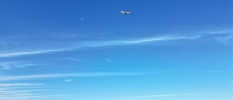 Un cielo azul despejado con un avión volando sobre un mar tranquilo.