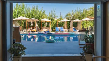A pool area with lounge chairs and umbrellas, surrounded by potted plants.