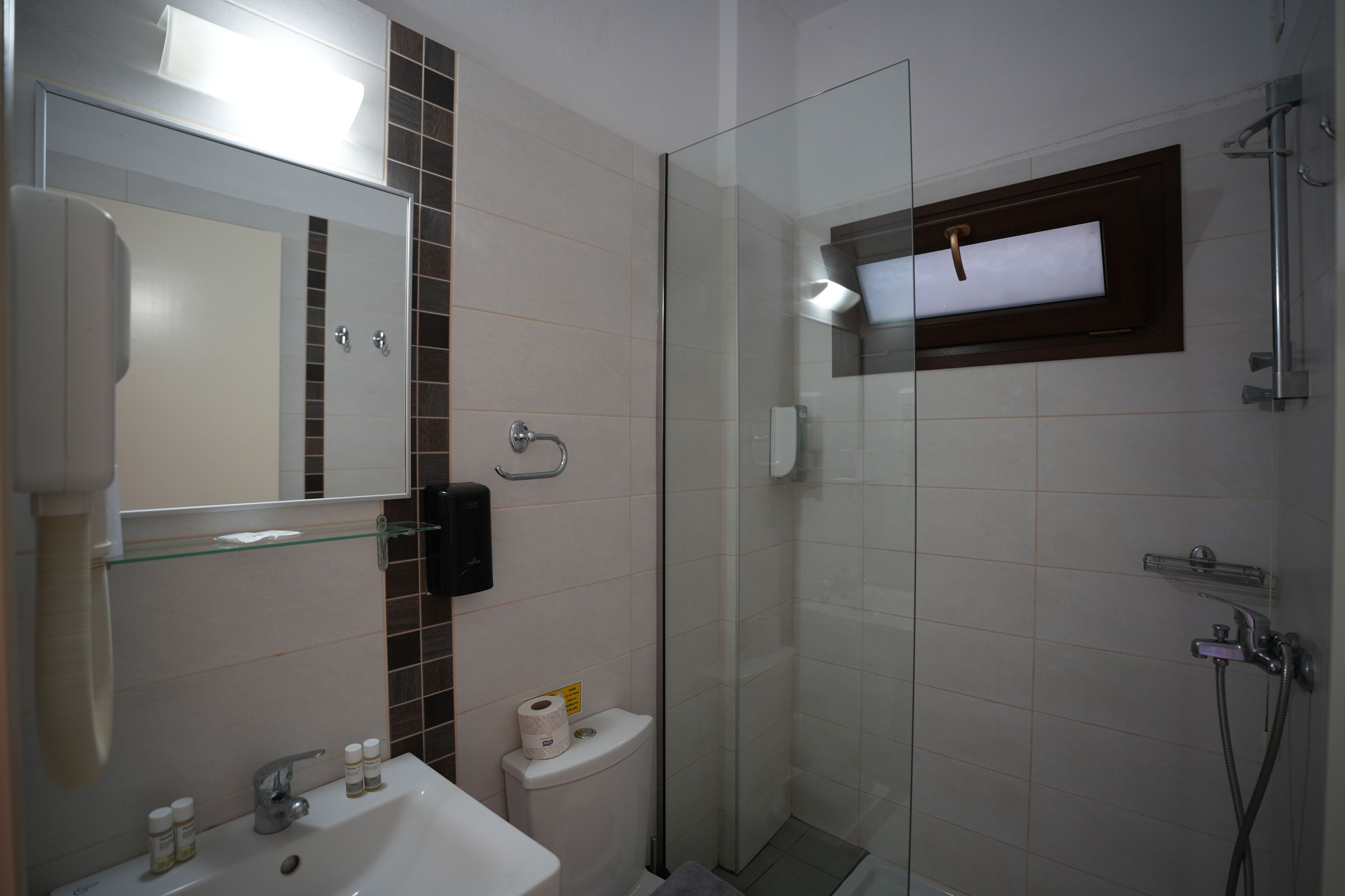 A bathroom with a glass shower enclosure, a sink with a mirror, and a toilet.