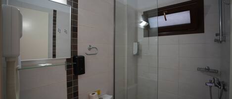A bathroom with a glass shower enclosure, a sink with a mirror, and a toilet.