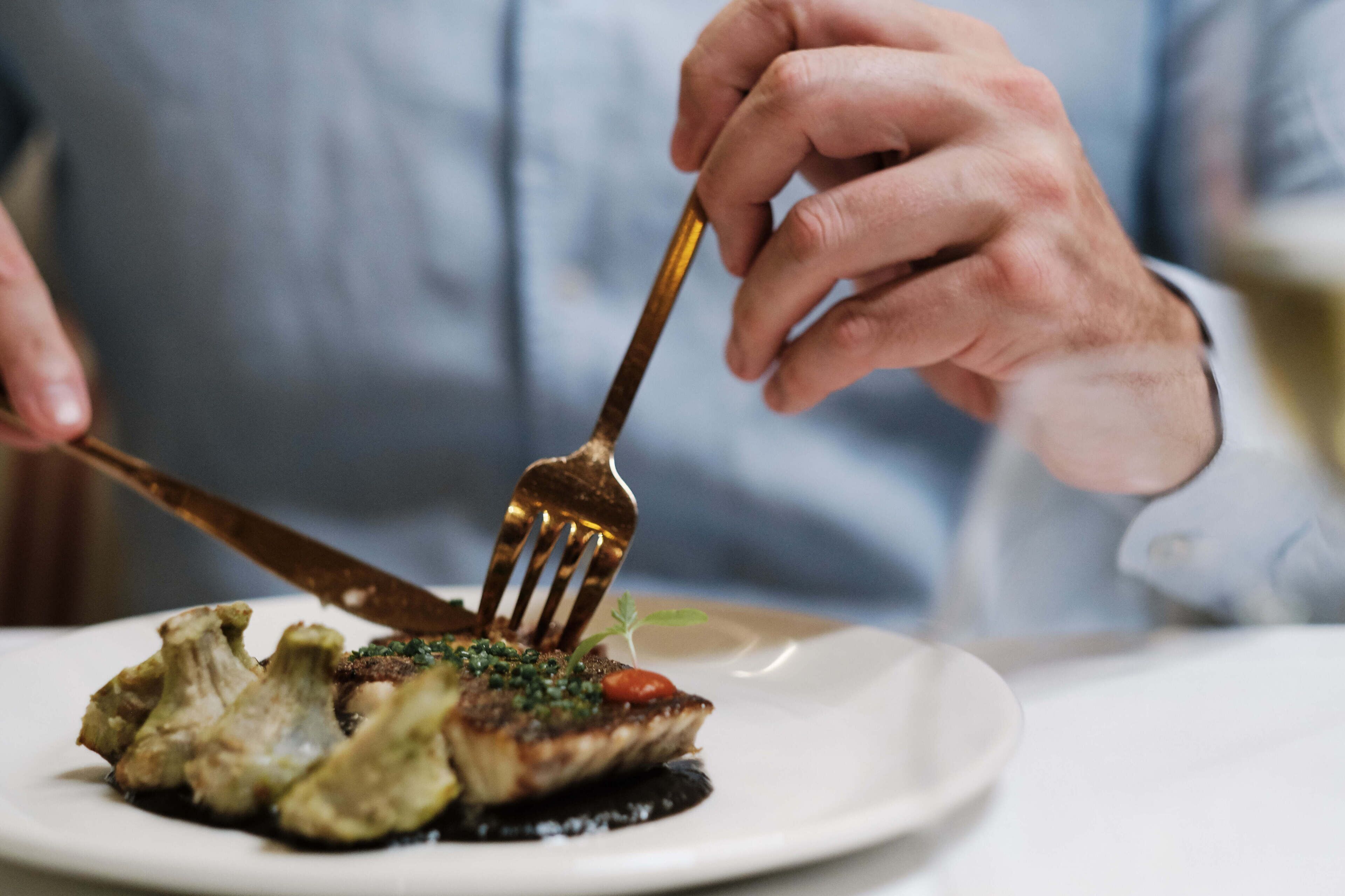 Una persona sosteniendo un tenedor con un bocado de comida en un plato.