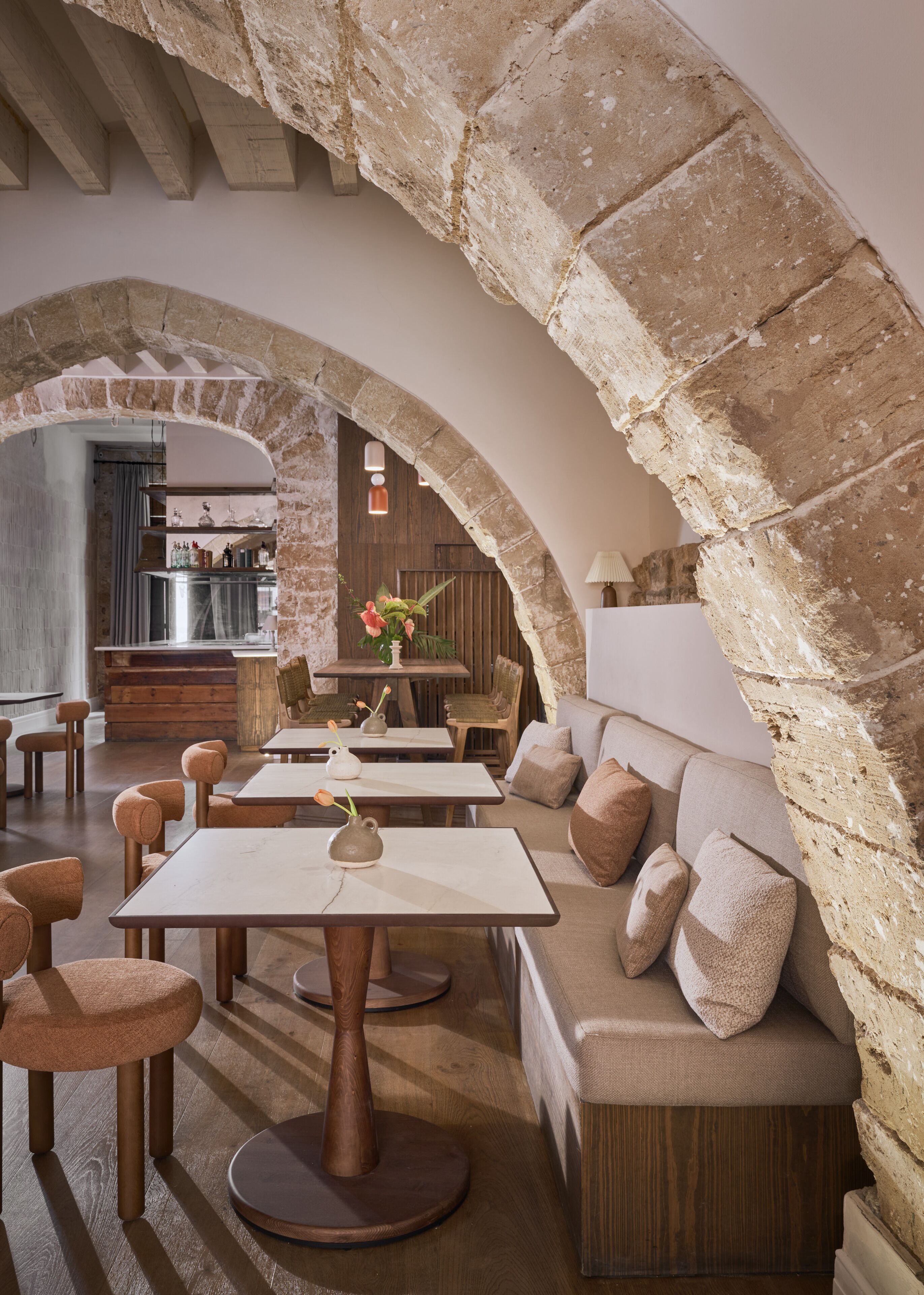 A cozy interior with stone arches, wooden furniture, and a modern kitchen in the background.