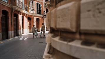 Eine enge Kopfsteinpflasterstraße mit historischen Gebäuden, ein Mann zu Fuß unterwegs und ein Radfahrer.