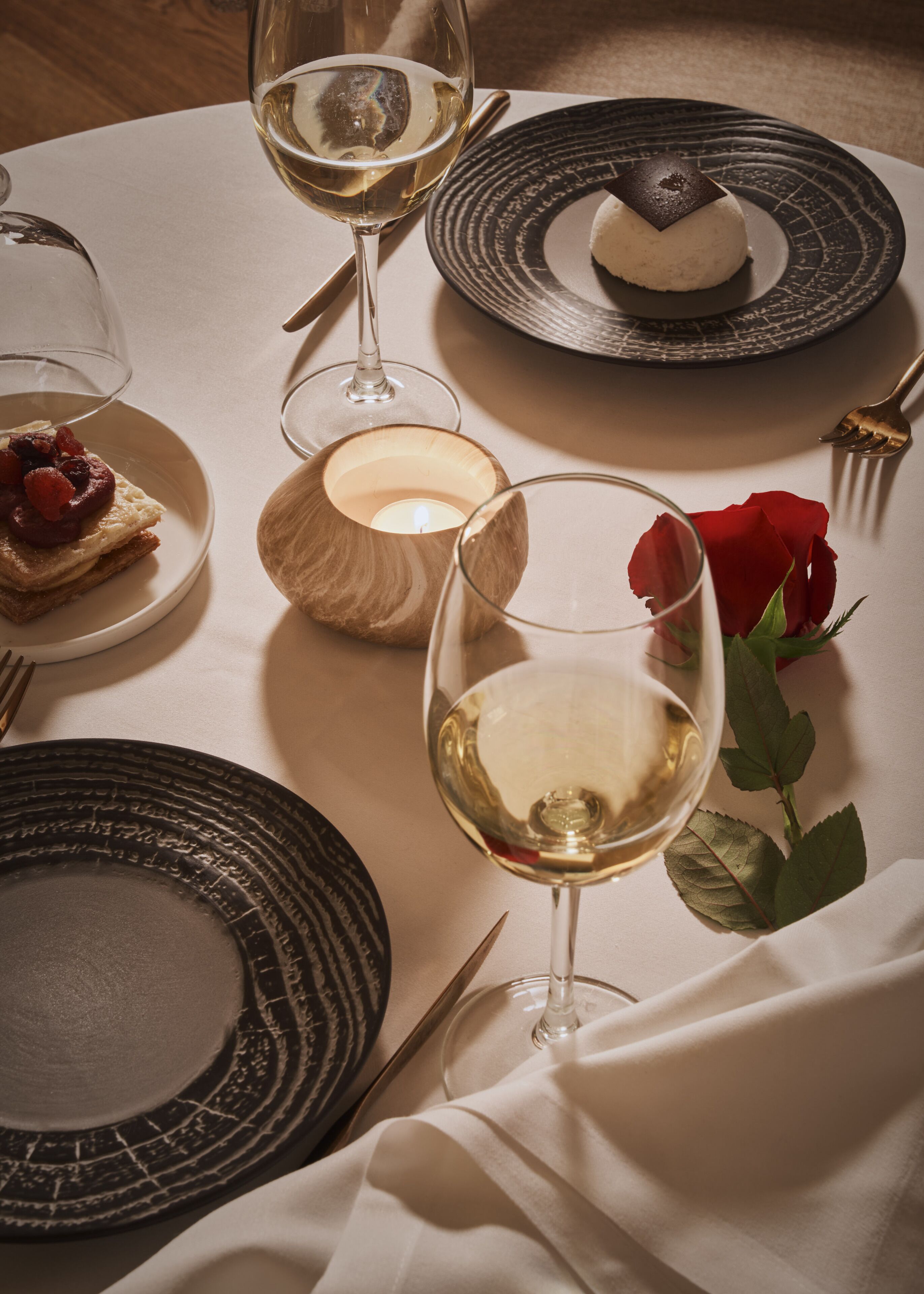 Une table mise pour un repas, avec des assiettes, des verres et une bougie.