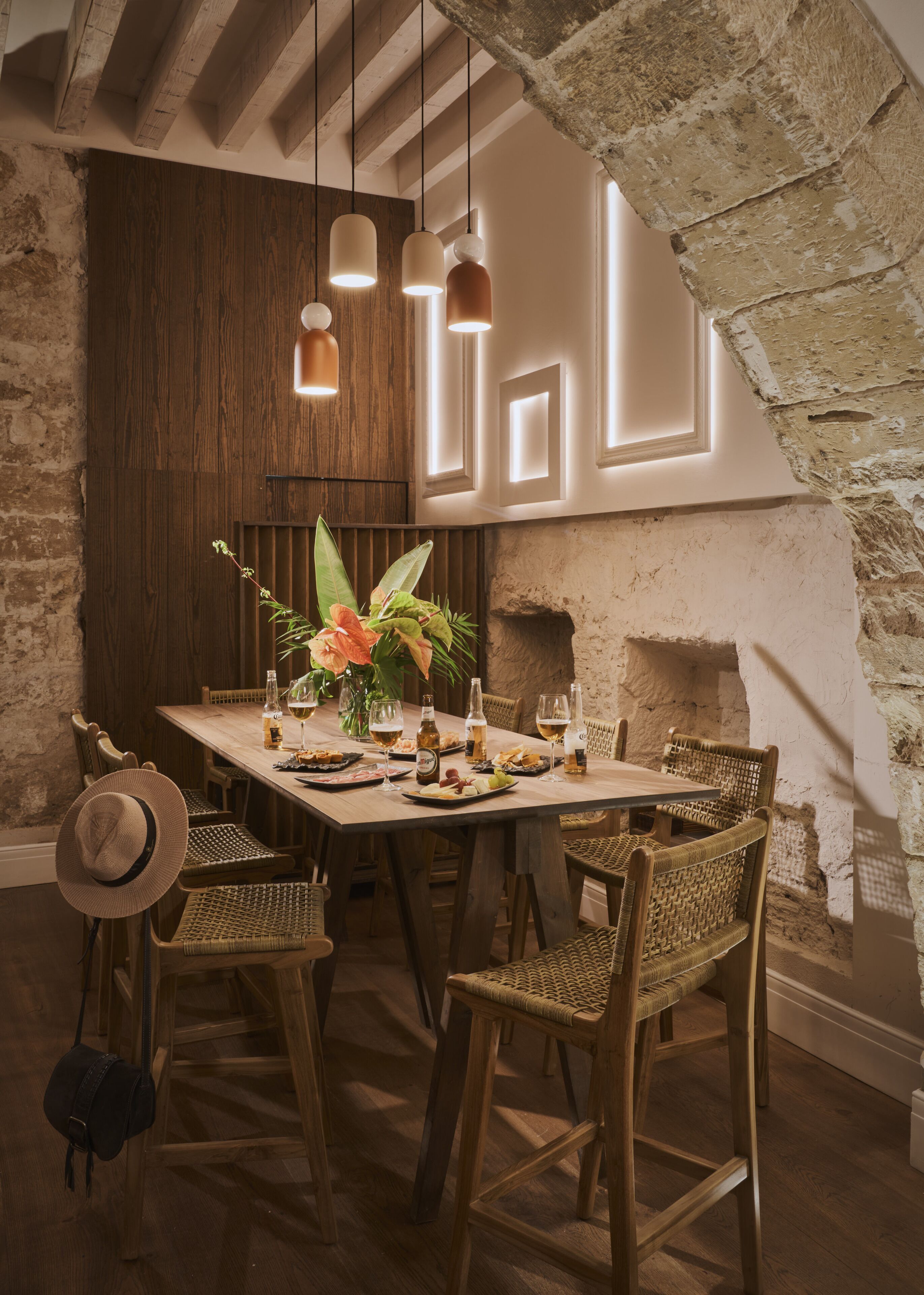 A dining area with a rustic wooden table, wicker chairs, and hanging pendant lights.