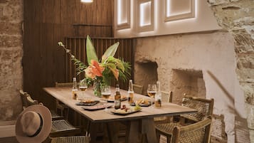 A dining area with a rustic wooden table, wicker chairs, and hanging pendant lights.