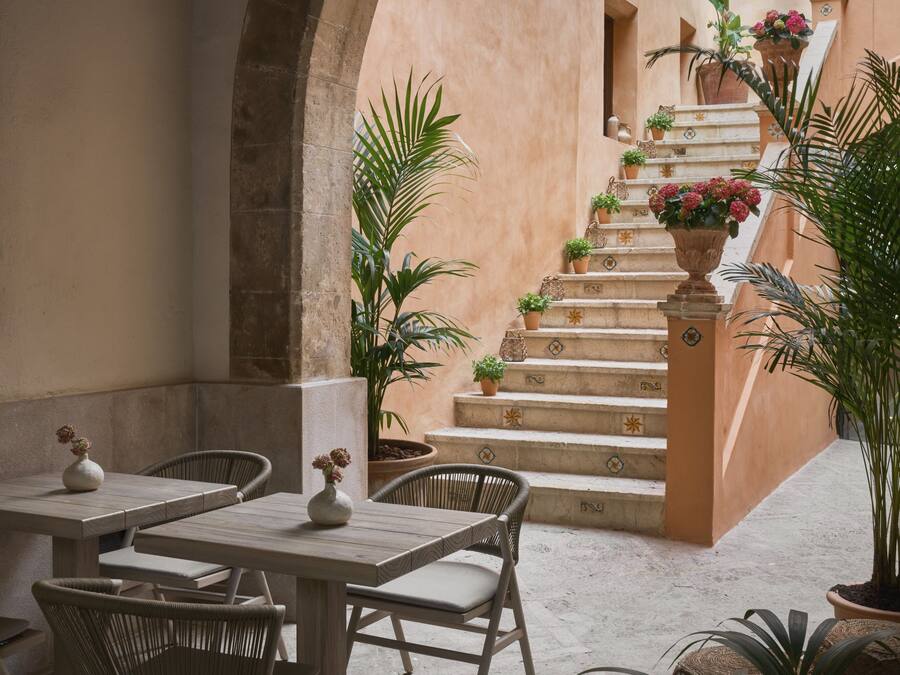 Un patio al aire libre con una escalera de piedra, muebles de mimbre y plantas en macetas.
