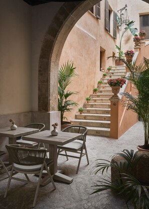 Un patio al aire libre con una escalera de piedra, muebles de mimbre y plantas en macetas.