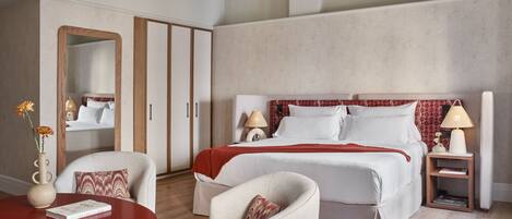A hotel room with a bed, two chairs, a small table, a mirror, and a nightstand with lamps.