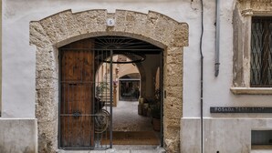 Una entrada arqueada con puerta de madera y reja de metal, que da a un camino empedrado.