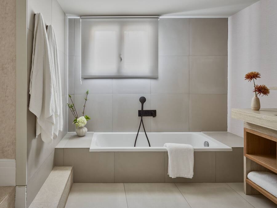 A modern bathroom with a freestanding bathtub, a window, and a small plant on the vanity.