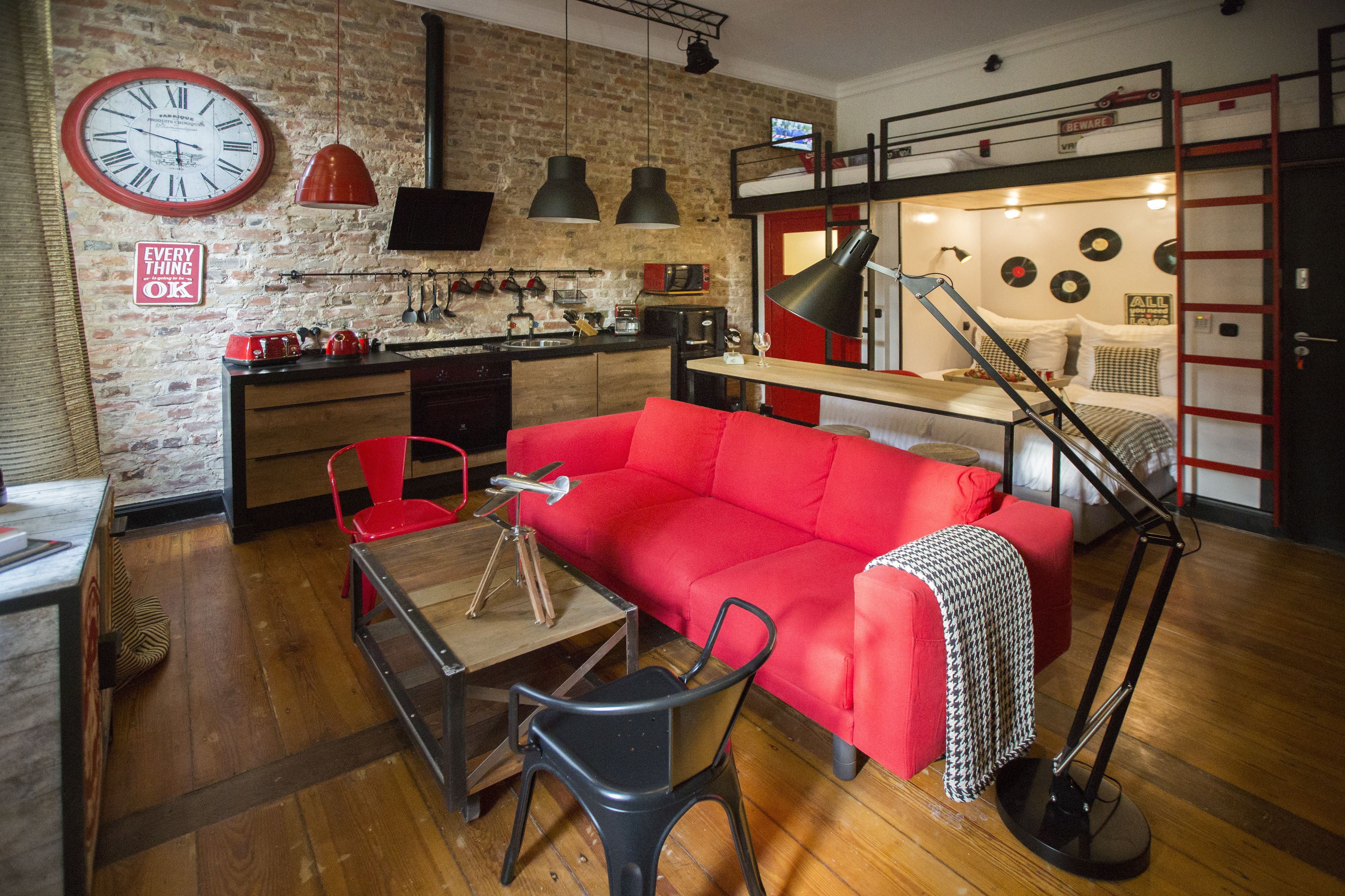A compact living space with a red sofa, a dining table, and a kitchen area.