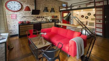 A compact living space with a red sofa, a dining table, and a kitchen area.