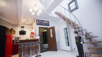 A modern kitchen with a red refrigerator, a wooden bar counter, and a chandelier.