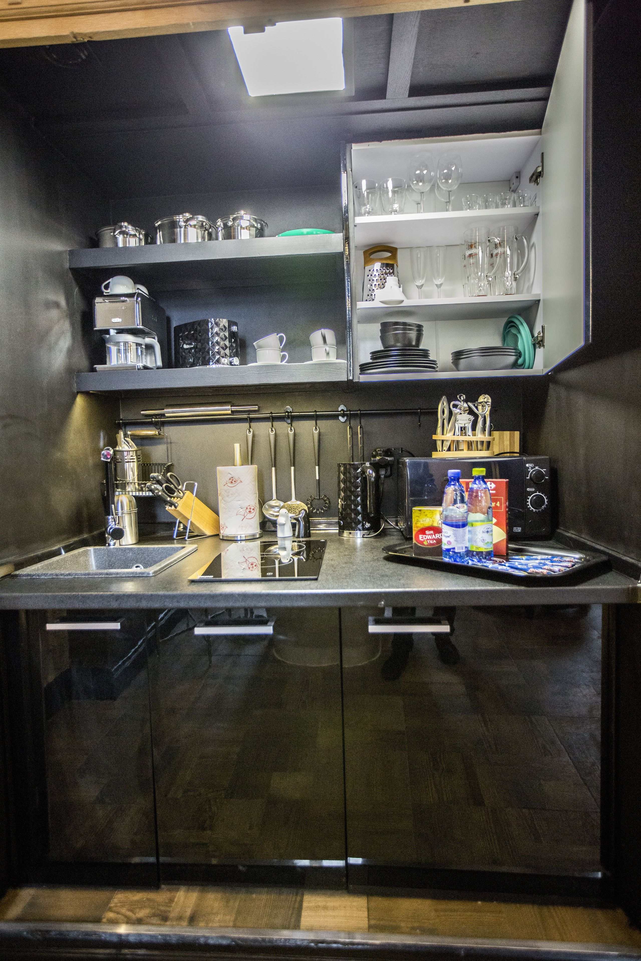 Une cuisine moderne équipée d’appareils électroménagers en acier inoxydable, d’une machine à café et d’une variété de verres disposés sur des étagères.