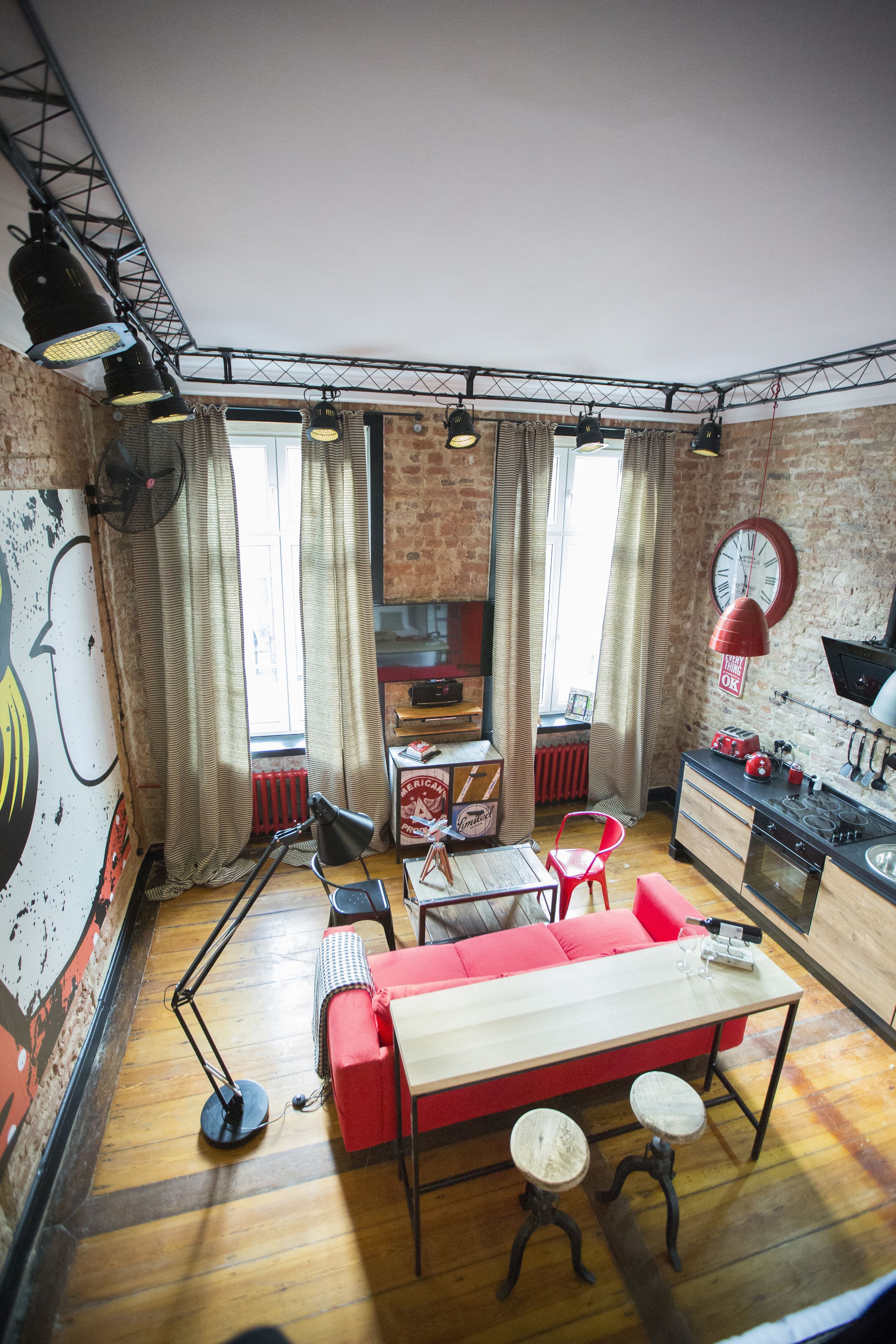 A compact living space with a kitchenette, a dining area with a red sofa, and a small kitchen counter.