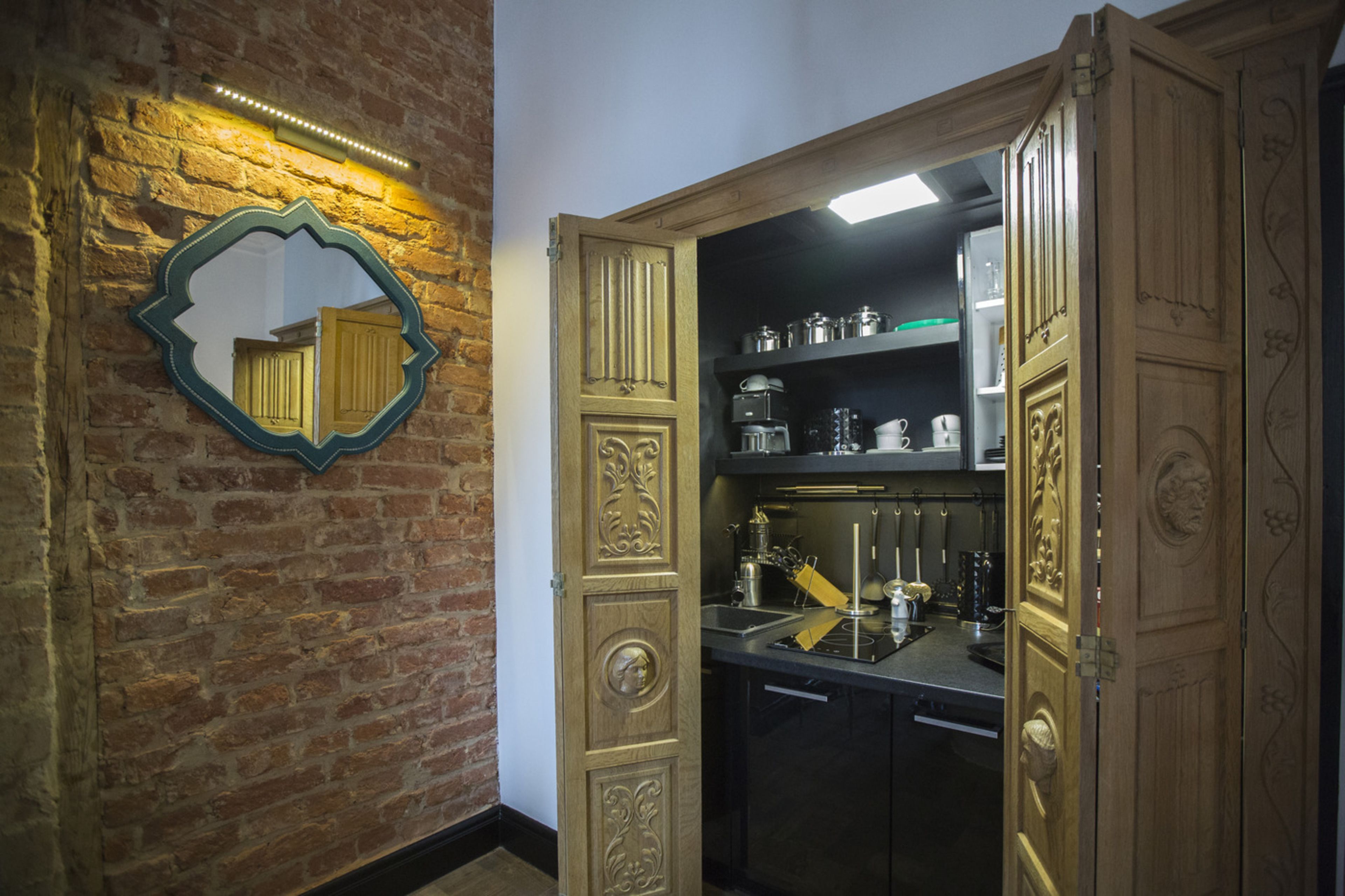 A kitchen with a brick wall, a decorative mirror, and wooden cabinetry.