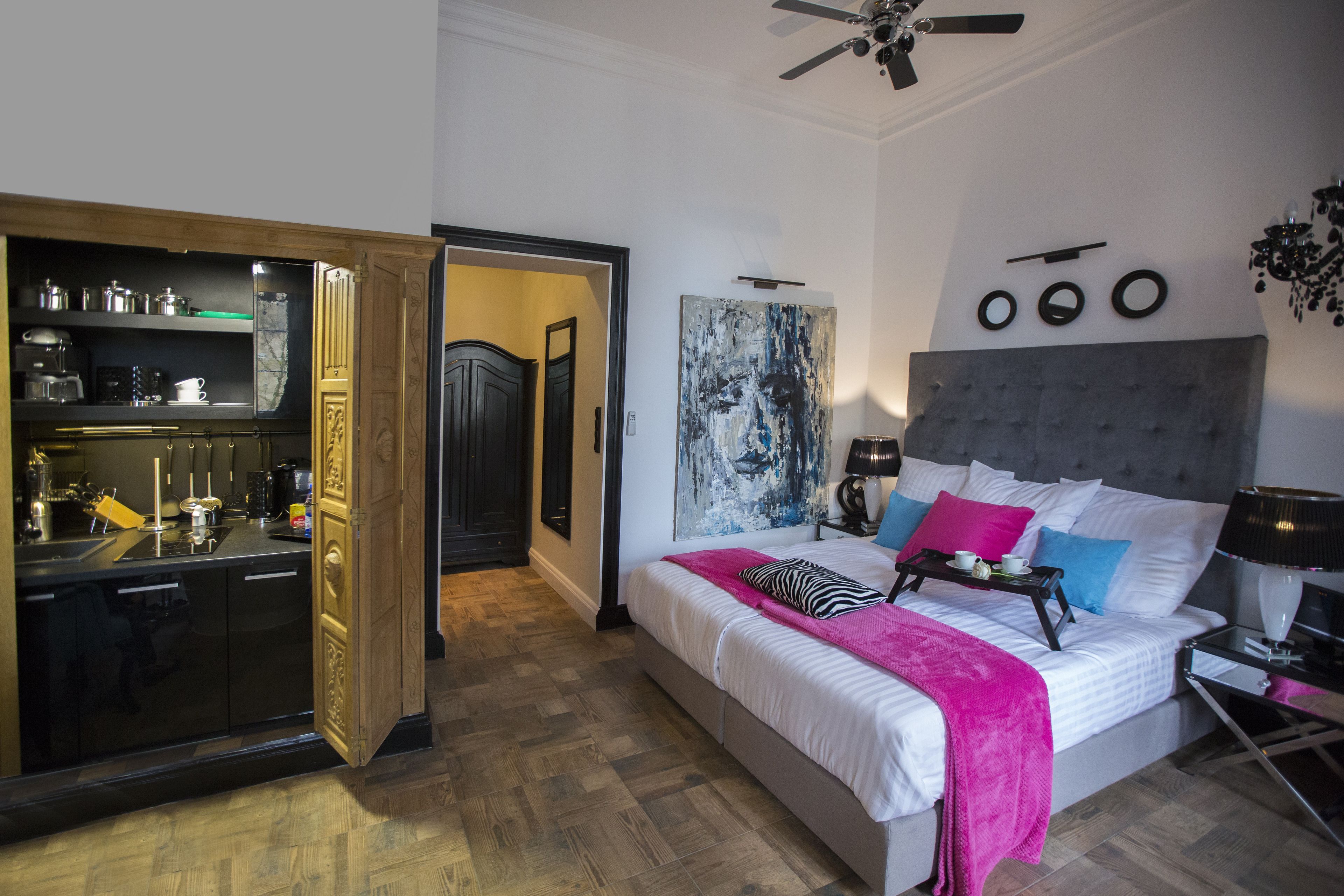 Un dormitorio con cama, mesitas de noche, un armario y una zona de cocina.