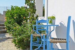 A blue chair and table set against a white wall, with a potted plant on the table. - Dilino Hotel (Naxos)
