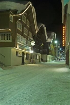 A snow-covered street at night with buildings on either side. - Gasthaus Skiklub (Andermatt)