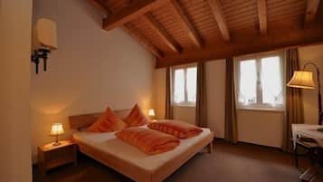Un dormitorio con techo de madera, una cama con ropa de cama naranja, dos lámparas de noche y un ventanal con cortinas.