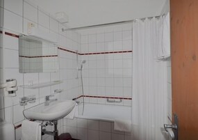 Un baño con lavamanos, espejo y ducha blancos.