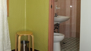 A bathroom with a toilet, sink, and fan. There is a wooden stool and a trash can. - Samwonjang Motel (Busan)