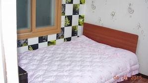A single bed with a wooden headboard in a room with a checkered wall pattern and floral wall decals. - Samwonjang Motel (Busan)