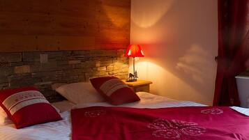 Een slaapkamer met een stenen muur, een houten hoofdbord, een rode lamp en een bed met rode beddengoed.