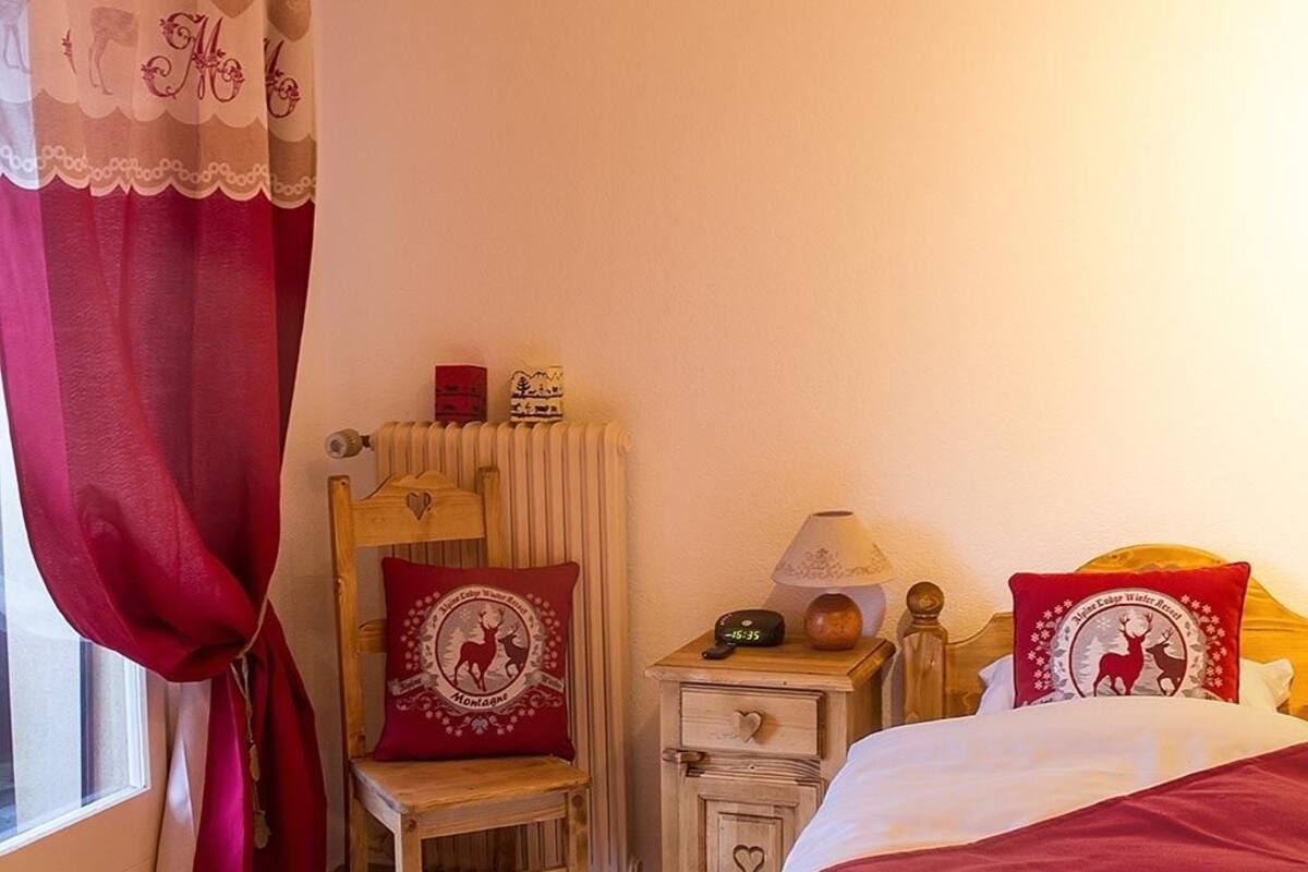 A cozy bedroom with a wooden headboard, a bedside table with a lamp, and decorative pillows.