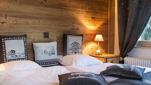 A cozy room with wooden walls, a bed with white bedding, and a nightstand with a lamp. - Hotel-Restaurant de la Poste (Ayent)