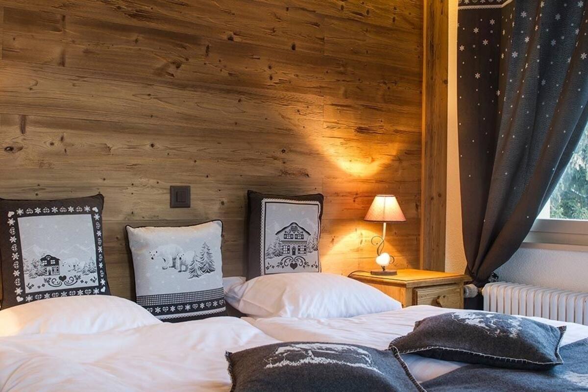 A cozy room with wooden walls, a bed with white bedding, and a nightstand with a lamp.