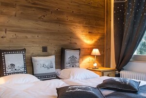 Una habitación acogedora con paredes de madera, una cama con ropa de cama blanca y una mesita de noche con una lámpara.
