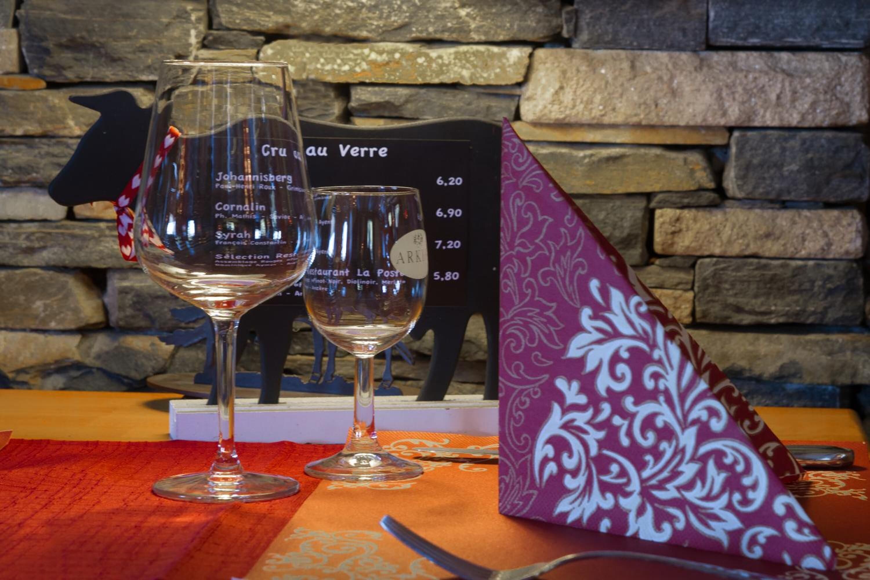 Two wine glasses on a table with a menu in the background.