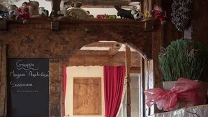 A rustic wooden interior with a chalkboard menu listing food items, a wooden bench, and a rustic door. - Hotel-Restaurant de la Poste (Ayent)