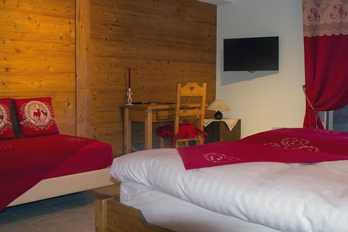 A hotel room with two beds, wooden walls, a TV, a desk, and a chair.