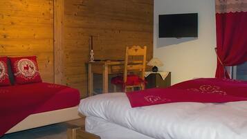 Quarto de hotel com duas camas, paredes de madeira, televisão, escrivaninha e uma cadeira.