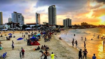 Perto da praia, areia branca, guarda-sóis, prática de ioga na praia