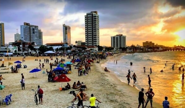 Perto da praia, areia branca, guarda-sóis, prática de ioga na praia 