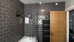 A modern bathroom with a freestanding bathtub, a shower, and a wooden door. - Elephant & Castle (Holmfirth)