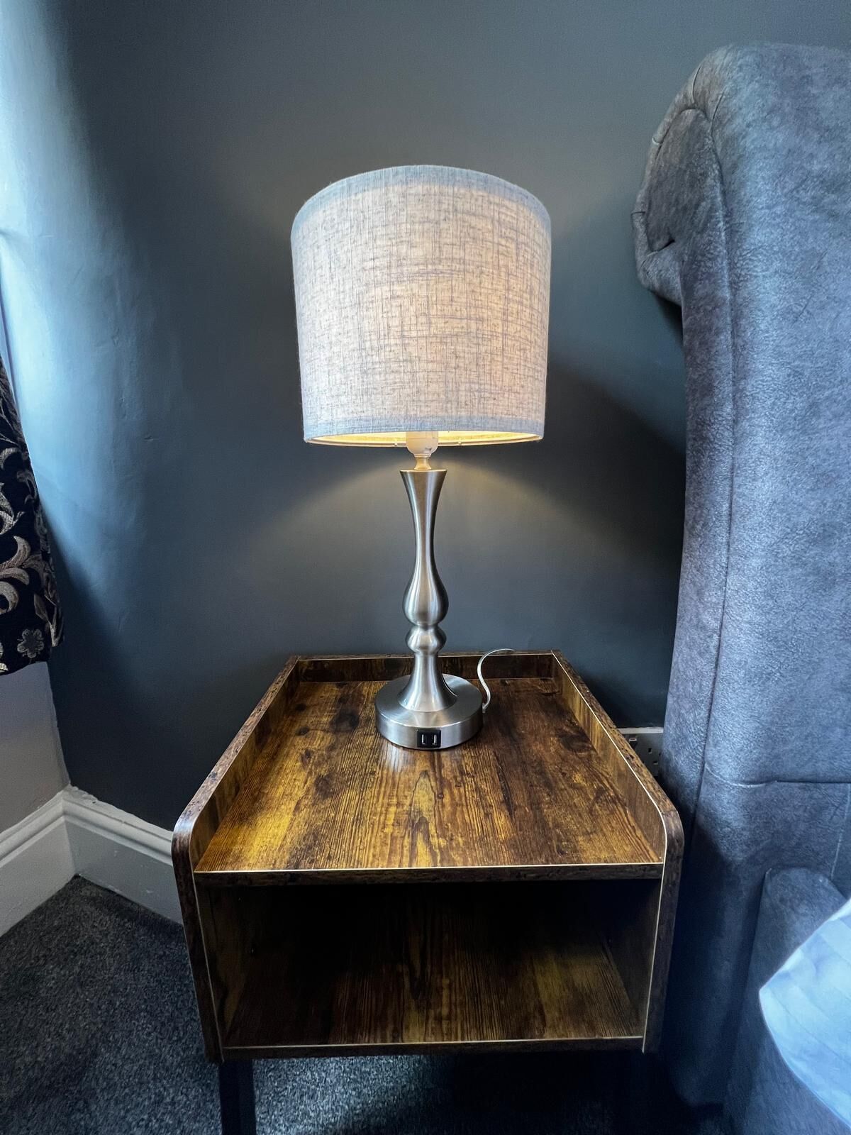 Een moderne tafellamp met een geribbelde lampenkap op een houten bijzettafeltje.