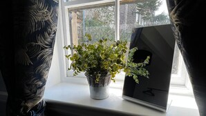 A window with a potted plant and a framed picture on the windowsill. - Elephant & Castle (Holmfirth)