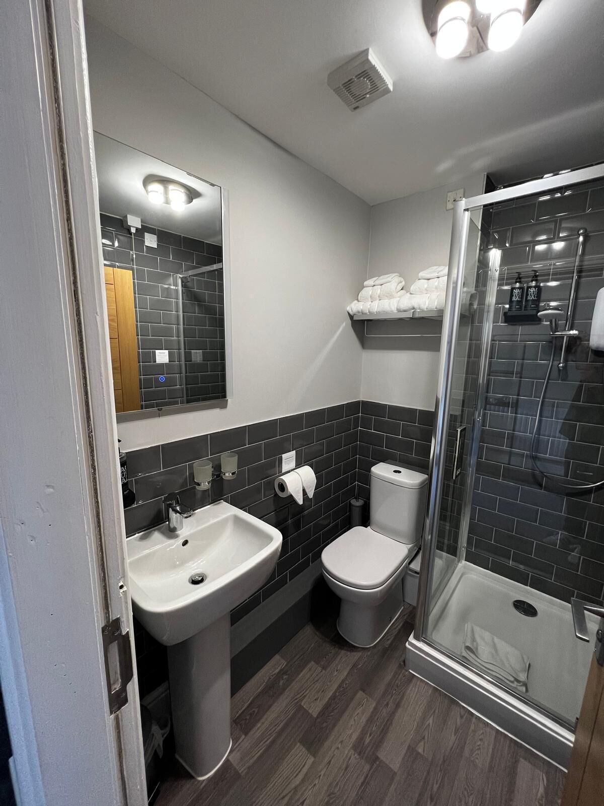 Un baño moderno con lavamanos blanco, inodoro y ducha con mampara de vidrio.
