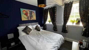 Un dormitorio con una cama grande, un cuadro en la pared y una ventana con cortinas.