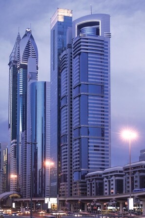 A cityscape with modern skyscrapers, a curved bridge, and a busy street with vehicles. - Carlton Downtown (Dubai)