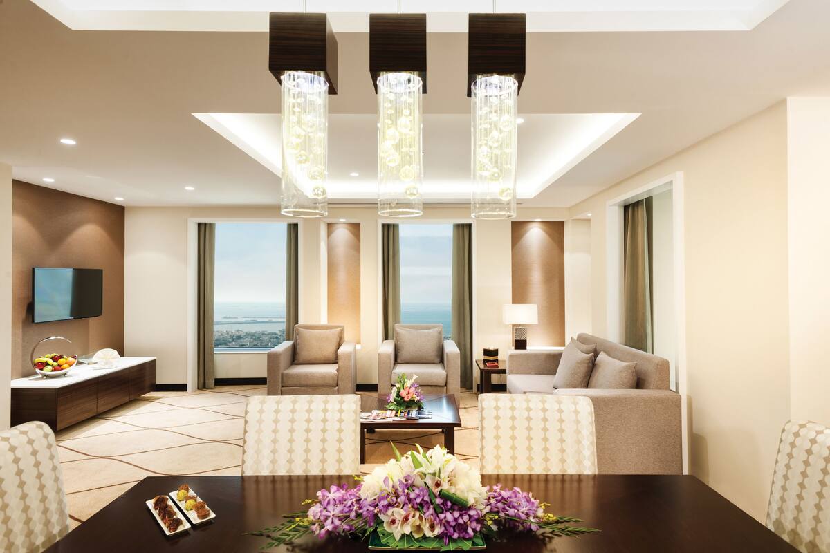 Un hall d’hôtel moderne avec une grande table à manger, des sièges confortables, un téléviseur et une vue sur la ville.