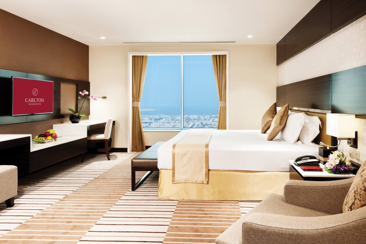 Une chambre d’hôtel avec un lit, un bureau, une télévision et une vue sur la ville.