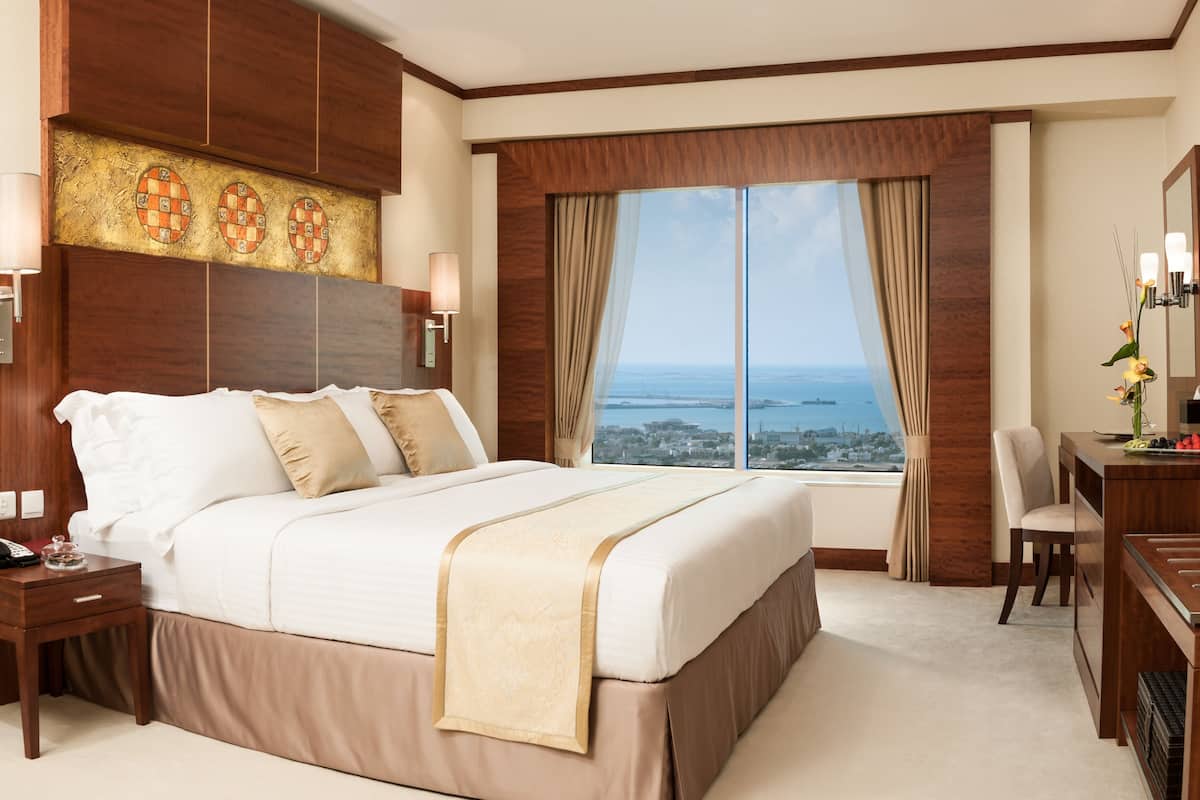 Une chambre d’hôtel avec un grand lit, un bureau, une chaise, une télévision et une fenêtre donnant sur la ville.