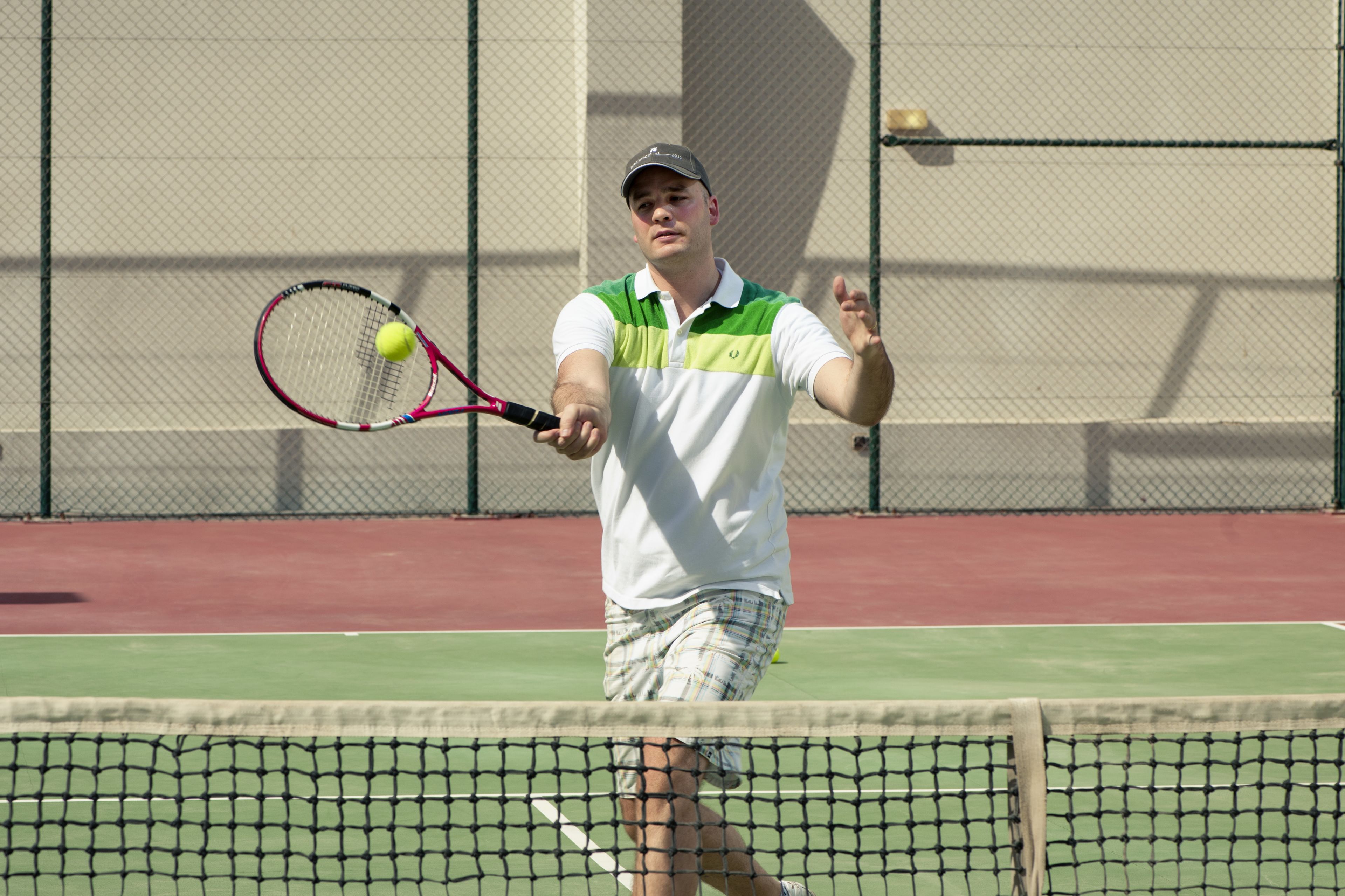 A tennis player on a court with a net in the foreground.