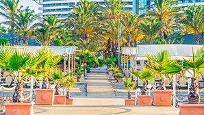 A pathway lined with palm trees leading to a modern building with multiple floors and balconies. - Royal Wings Hotel - All Inclusive (Antalya)
